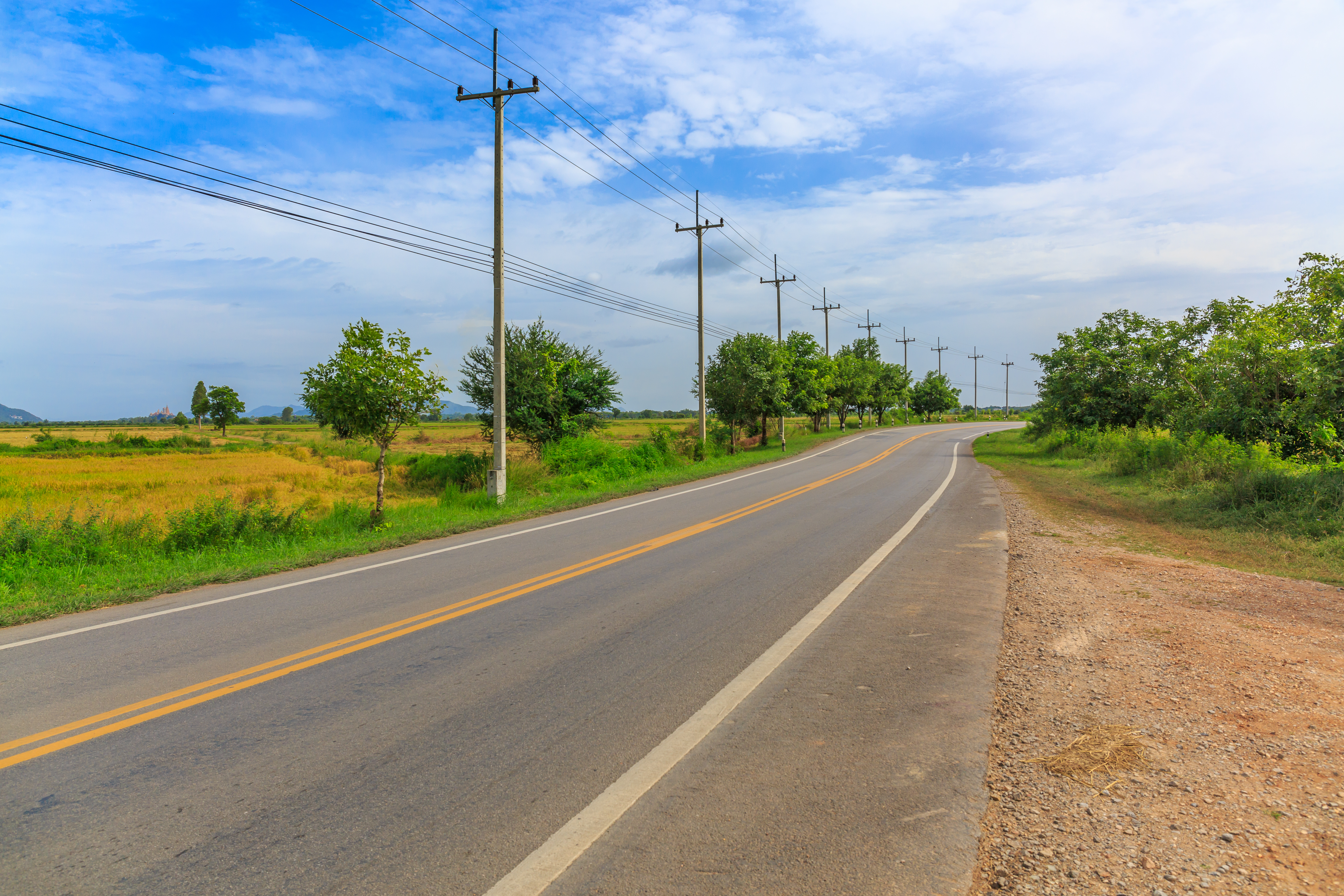 Country road with powerlines next to farming lands 